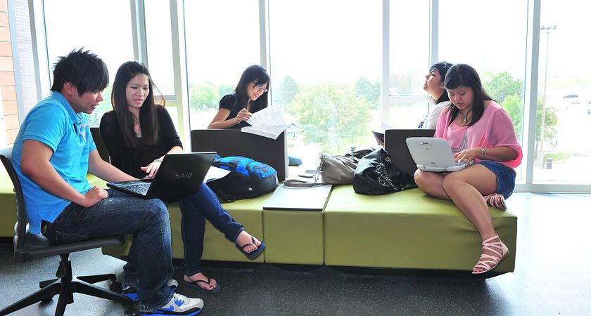 A group of students relax on a couch in the library